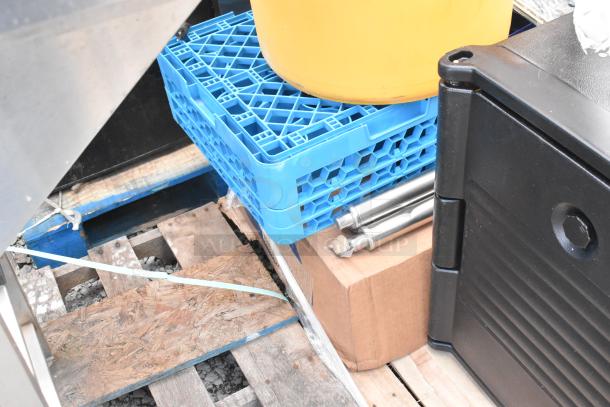 Assorted scratch and dent items including blue dish caddies, a black trash can, and metal rods on a wooden pallet.
