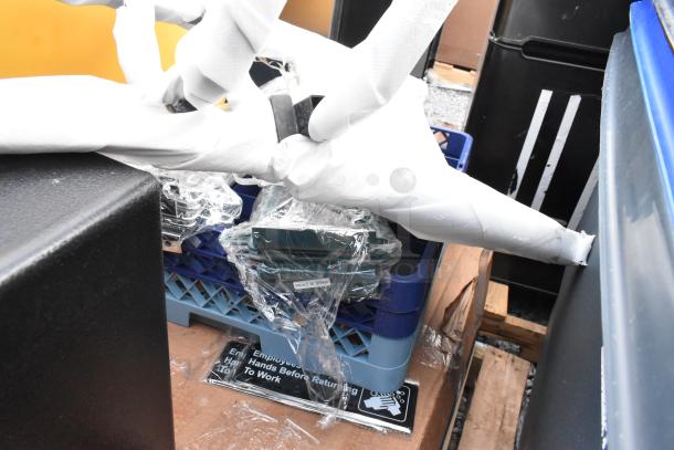 A collection of new, scratch, and dent items, including trash cans and dish caddies, partially wrapped and stacked, labeled "Made in China."