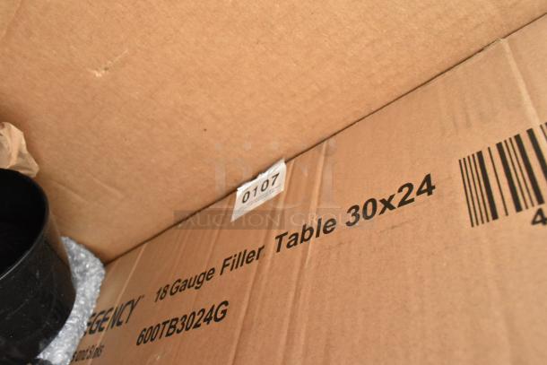 Cardboard box labeled "18 Gauge Filler Table 30x24," with auction tag "0107" visible. Contains scratch and dent items.