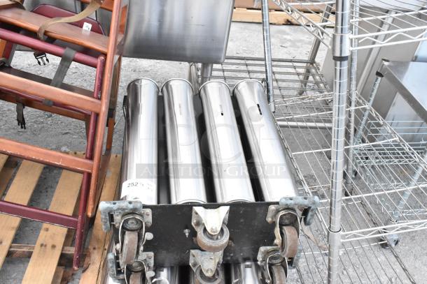 Wooden high chair with straps next to stainless steel cup dispenser on wheels. Slight wear visible. Auction tag numbered 252.