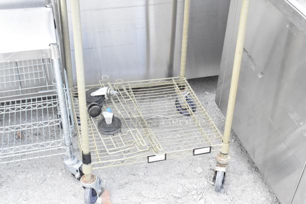 Two 2-tier wire shelving units on commercial casters, one missing casters. Requires dismantling for shipping.