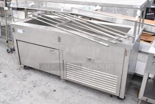 Stainless steel commercial buffet station with storage, equipped with commercial casters for mobility, in used condition.