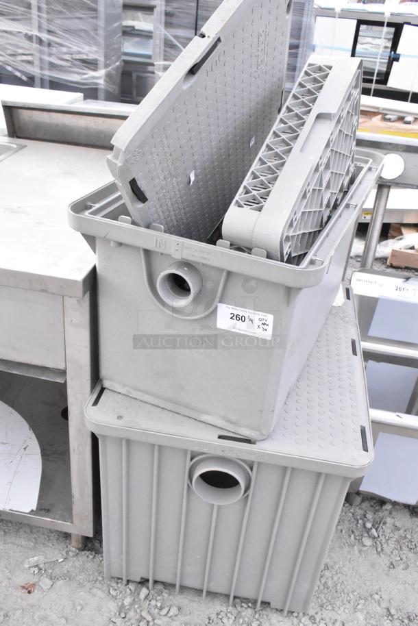 Stacked grease traps and a dish caddy, gray, durable plastic with in/out ports. Visible auction tag reading "260½ QTY x3."
