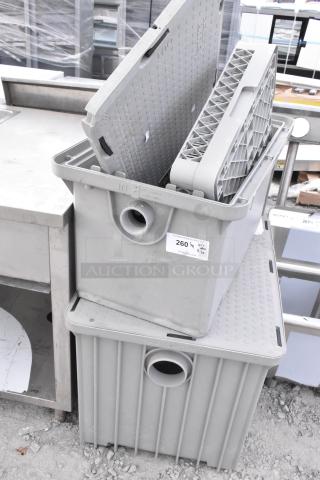 Stacked grease traps and a dish caddy, gray, durable plastic with in/out ports. Visible auction tag reading "260½ QTY x3."