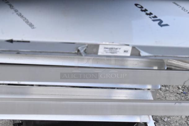 Regency metal commercial pan transport rack, brand new, slight scratches and dents visible, with label showing model specs.