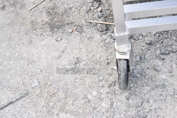 Regency metal commercial pan transport rack with wheel on rough surface, showing new condition despite scratch and dent.