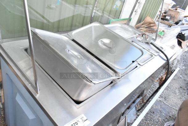Stainless steel 4-bay electric steam table with sneeze guard, tray slide, and inserts, in good condition.