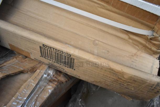 Cardboard box labeled 522ETSG3030 containing a brand new Steelton 30" x 30" stainless steel work table.