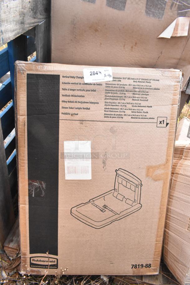Box of Rubbermaid commercial products, including a vertical baby changing station. Brown cardboard with product illustrations and specs.