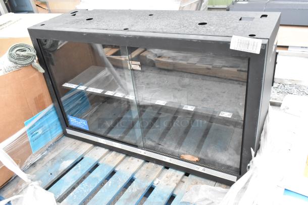 Metal 2-door dry merchandising cabinet with glass doors, black frame, secure latch, visible price labels, and minor surface wear.