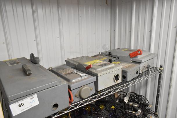 Five various power boxes on a metal shelf, featuring gray exteriors and red levers. Some show labels and slight wear.