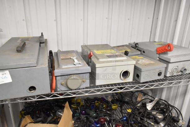 Five assorted power boxes on a metal shelf, various conditions, labeled with electrical specifications, ready for industrial use.