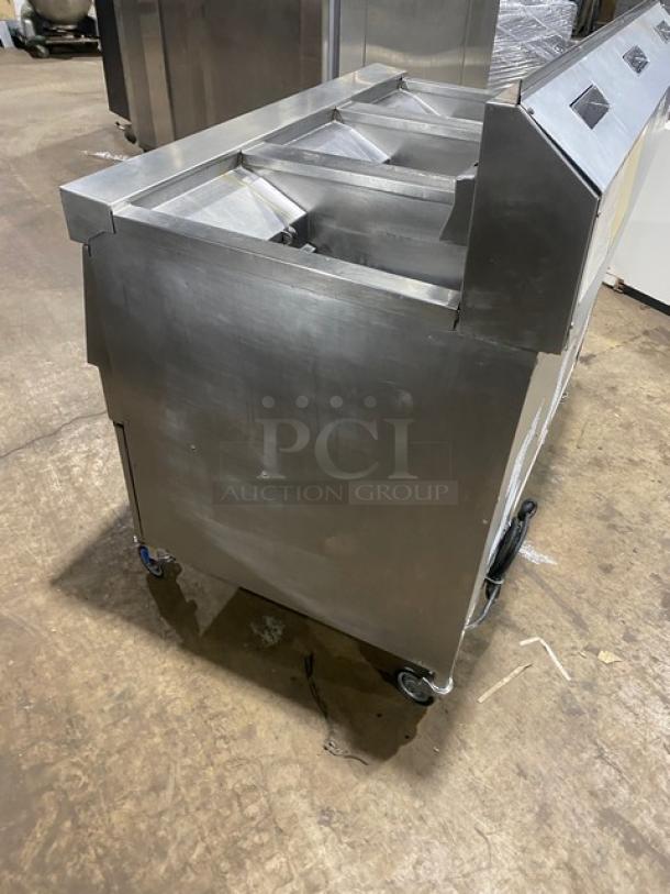 Henny Penny Evolution Elite EEG-253 stainless steel triple bay fryer, natural gas, with back splash and basket hanger, on casters.