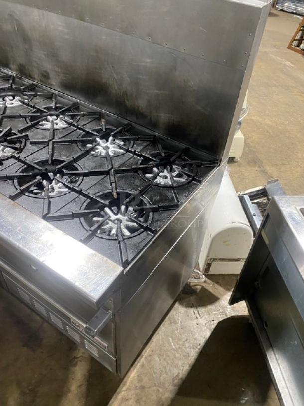 Garland commercial stainless steel 10-burner gas range with double oven, backsplash, wired oven rack, and casters.