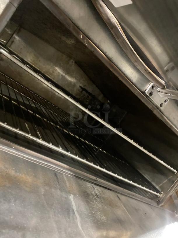 Commercial stainless steel gas-powered 3-compartment seafood steamer with individual controls and wired oven rack, shown open.