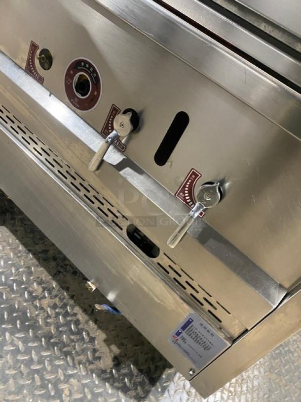 Commercial stainless steel gas-powered 3-compartment seafood steamer with individual controls, wired rack, on legs.