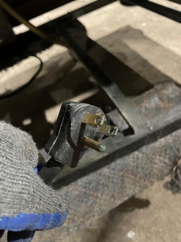 Close-up of a three-pronged electrical plug, likely for a commercial refrigerator. Plug appears in used condition.