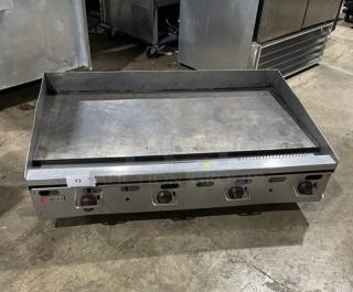 Wolf commercial stainless steel gas griddle with back and side splash, four control knobs, and sturdy legs; ideal for heavy-duty cooking.