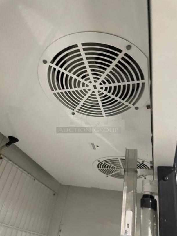 True GDM-49F commercial freezer interior view with fan, white interior, and poly-coated wire racks visible.