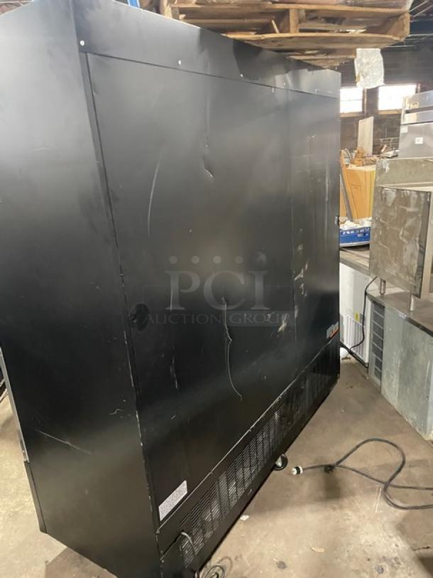 Spartan SGM72RS triple glass swing door refrigerator. Black powder-coated exterior, poly-coated wire racks, on casters, visible wear.