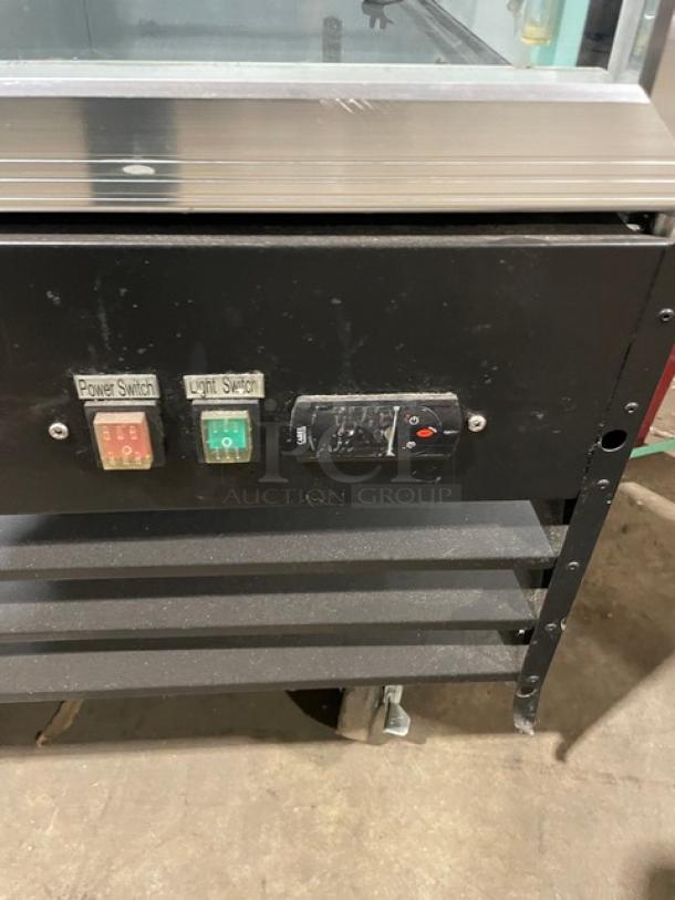 Spartan SGM-72RS triple glass door refrigerator, black powder-coated, poly wire racks, on casters, with power and light switches.