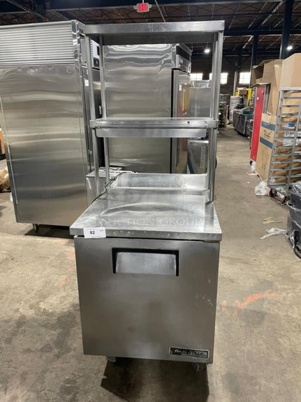 True TWT-27 stainless steel single door worktop refrigerator with backsplash and double overhead shelf. Includes poly-coated wired rack, on casters, 27" wide, model TWT-27, serial 1-4588258, 115V, 1 phase. Working condition.