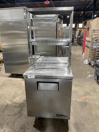 True TWT-27 stainless steel single door worktop refrigerator with backsplash and double overhead shelf. Includes poly-coated wired rack, on casters, 27" wide, model TWT-27, serial 1-4588258, 115V, 1 phase. Working condition.