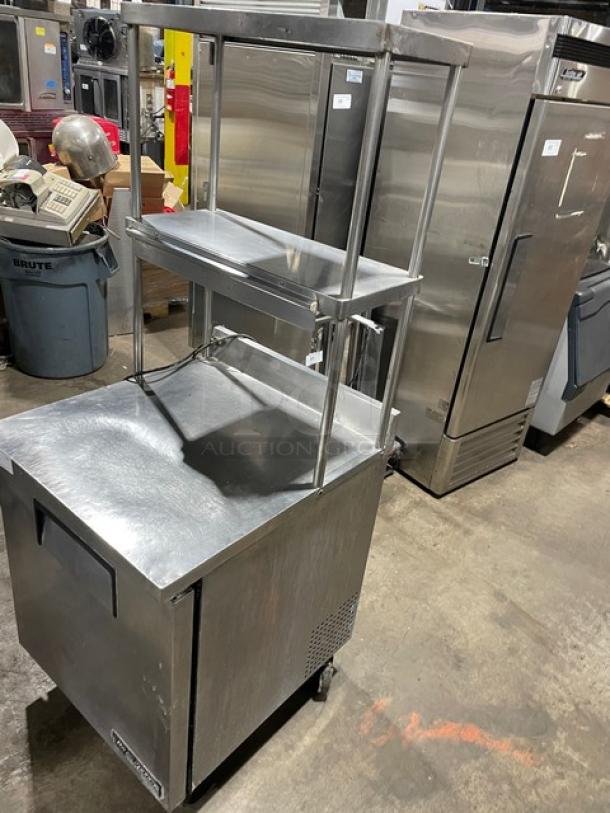 True TWT-27 commercial stainless steel refrigerator with backsplash, double overhead shelf, and poly coated rack on casters.
