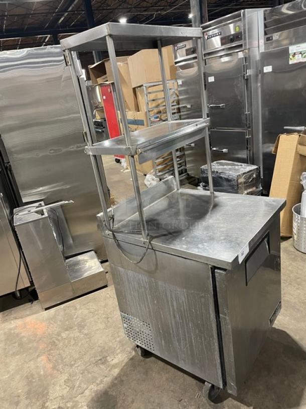 True TWT-27 stainless steel worktop refrigerator, 27", with backsplash, double overhead shelf, poly coated rack, on casters.