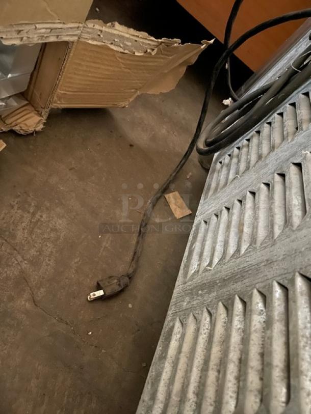 Leader NSFB27SC stainless steel undercounter refrigerator with poly coated wire rack, shown with power cord and metal vent panel.