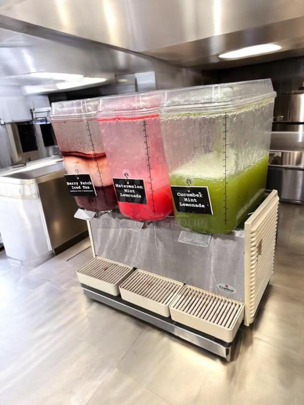 Crathco D35-4 beverage dispenser, 4-flavor, excellent condition, labels include Berry Patch Iced Tea, Watermelon Mint Lemonade, Cucumber Mint Lemonade.