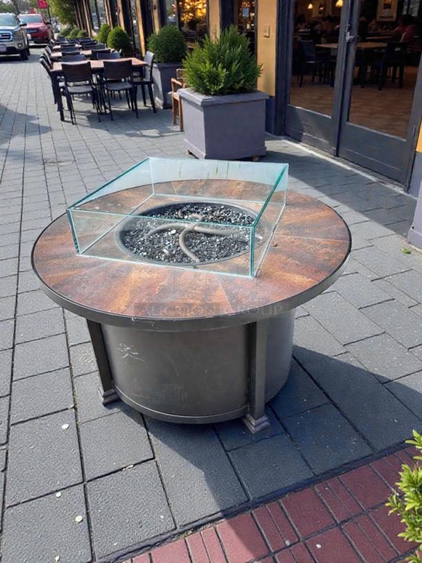 Round gas fire pit table, pristine condition, rust-colored top, glass shield, compatible with natural gas/propane. Fully inspected.