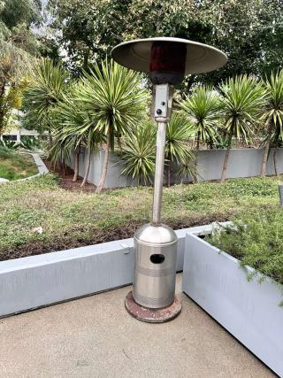 Stainless steel commercial patio heater with mushroom top, tested and in superior condition, outdoor setting.