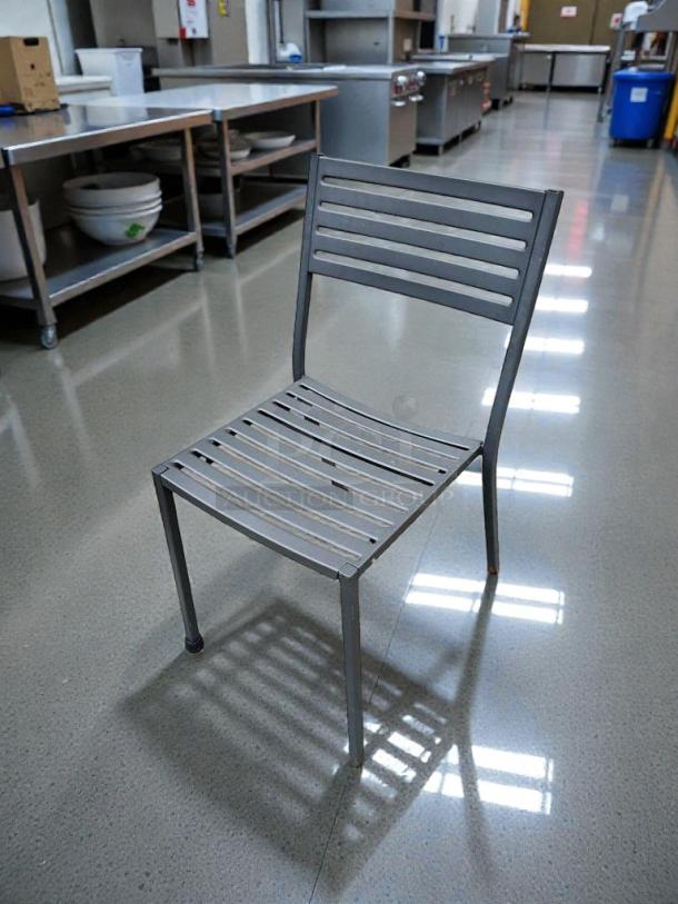 Commercial-grade metal patio chair in immaculate condition, slatted design, durable, fully inspected, ready for outdoor use.