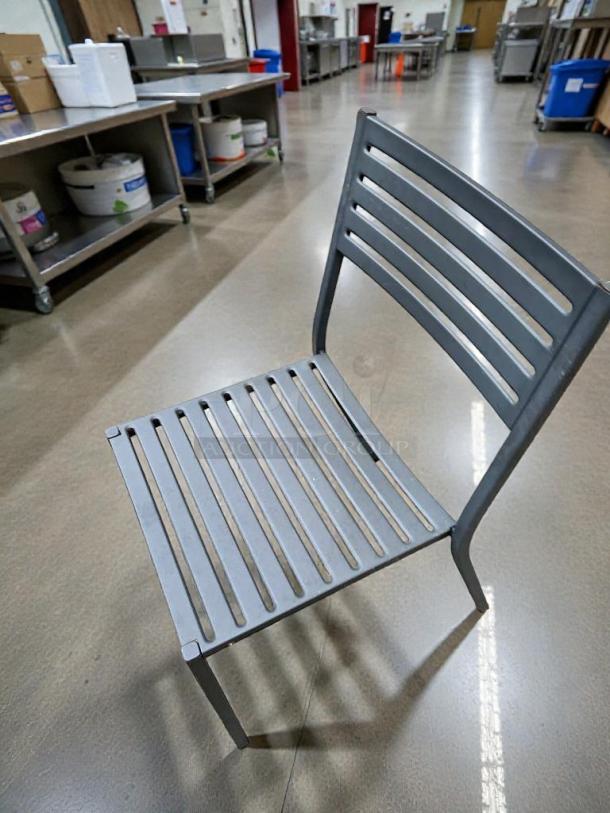 Commercial metal patio chair in immaculate condition, gray slatted design, ready for outdoor dining use.
