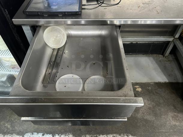 Stainless steel worktable by John Boos, model ST6R5-3060GBK, featuring one open drawer with some debris visible; table surface holds electronic device. Excellent condition, ready for use.