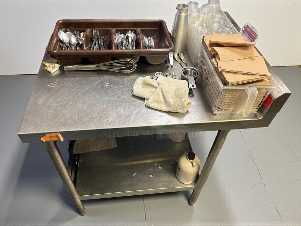 Omniteam stainless steel commercial work table with backsplash, sturdy, refined condition, fully tested, with utensils and containers.