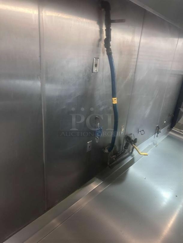 Commercial gas appliance connector hose, prime condition, attached to wall. Inspected, ready for use, yellow safety tag visible.