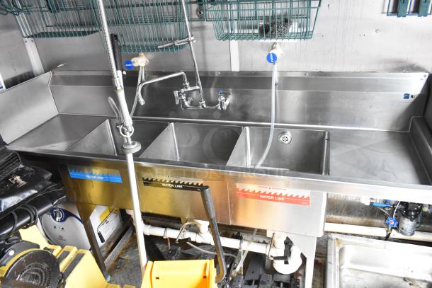 Stainless steel triple sink with faucet and labeled water lines in a commercial kitchen setup.