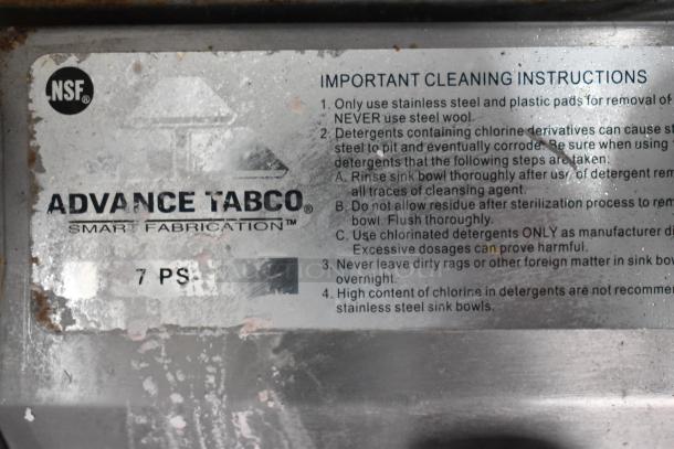 Advance Tabco cleaning instruction label on commercial kitchen equipment, noting stainless steel care tips and precautions.