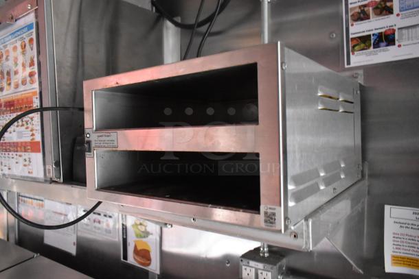 Commercial kitchen equipment in a fast food trailer, featuring a Henny Penny appliance sign. Wall-mounted instructions visible.