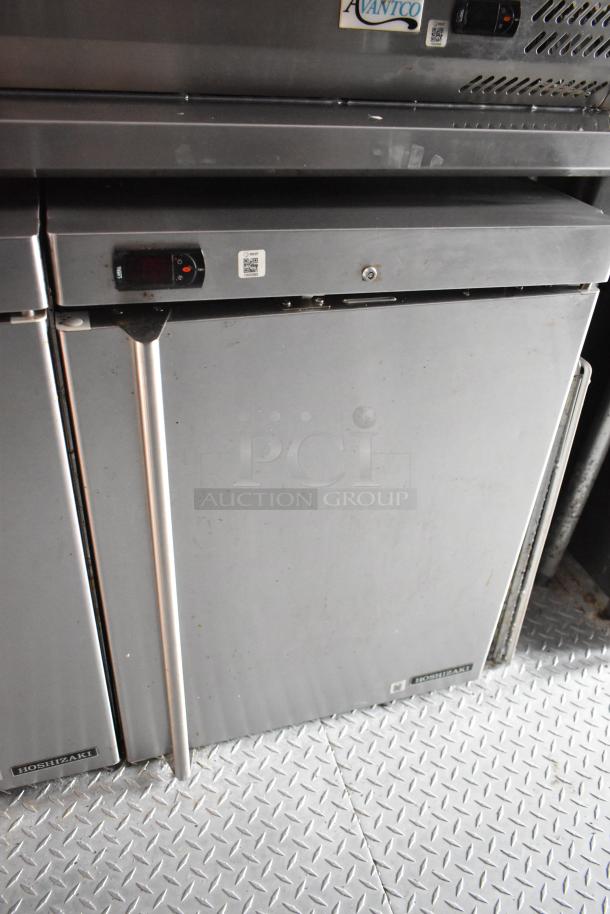 Stainless steel Hoshizaki undercounter refrigerator in Wendy's food trailer, featuring a digital display and latch handle.