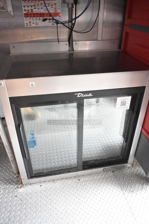 True merchandiser in mobile kitchen trailer, features glass doors, stainless steel exterior, and QR code. Great condition.