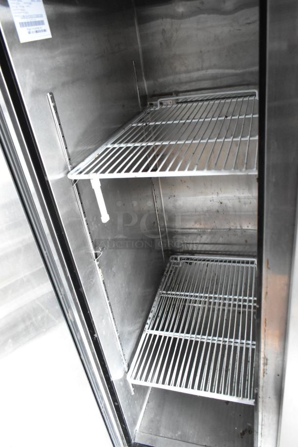 Interior of commercial fridge with metal wire shelves, showcasing ample storage space. Clean, stainless steel finish.