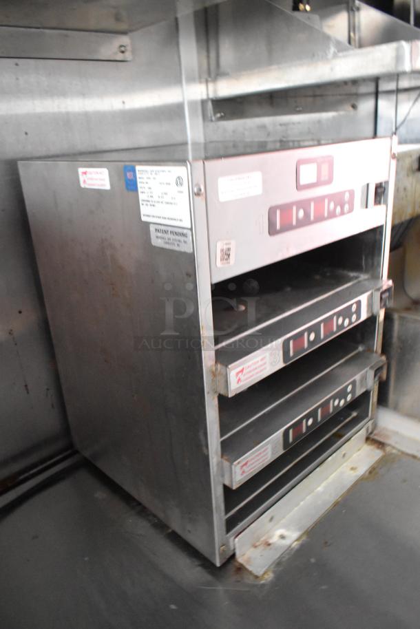 Stainless steel food warmer with digital controls and labels, showing signs of light use, inside a mobile kitchen trailer.