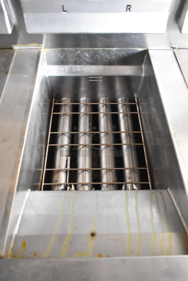 Commercial-grade stainless steel fryer with grease hood, featuring metal grill grate and visible drip marks, used condition.