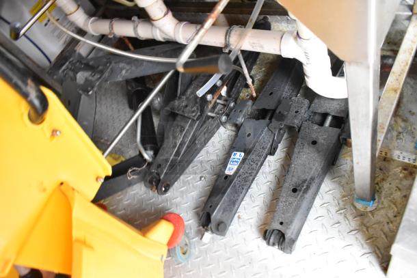 Interior view of a 28' Wendy's fast food trailer, showing pipes and metal components below fixtures. Diamond plate flooring is visible.