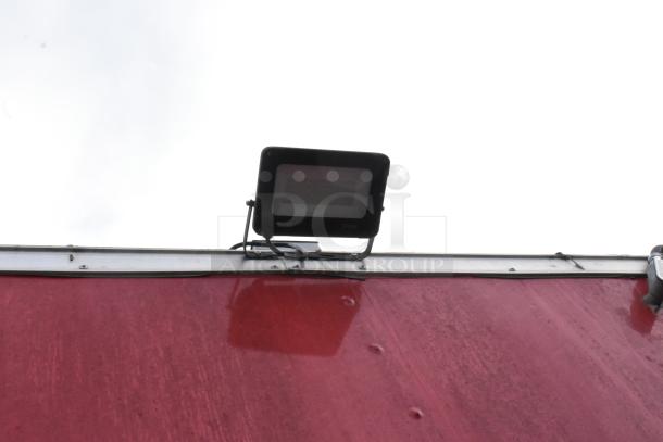Red exterior of 28' Wendy's fast food trailer with mounted 50W floodlight, part of fully equipped mobile kitchen setup.