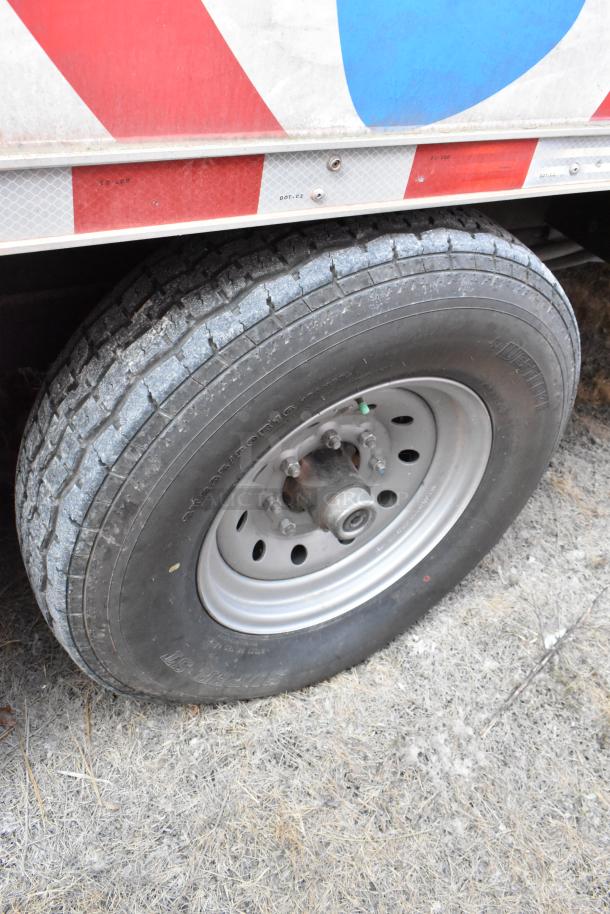 Close-up of tire on 2021 28' Wendy's fast food trailer, showcasing sturdy condition and part of vibrant exterior design.