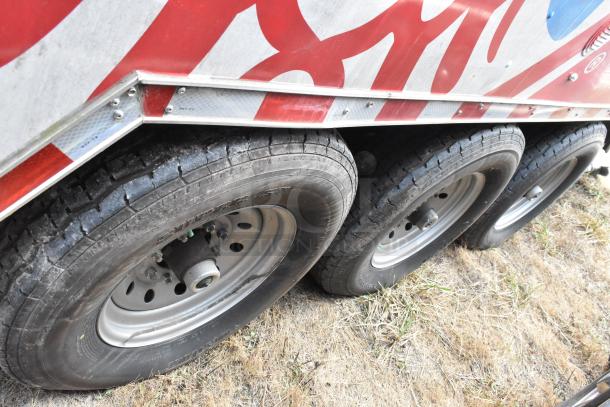 Close-up of the tires and lower side panel of a 28' Wendy's fast food trailer with red and silver design.